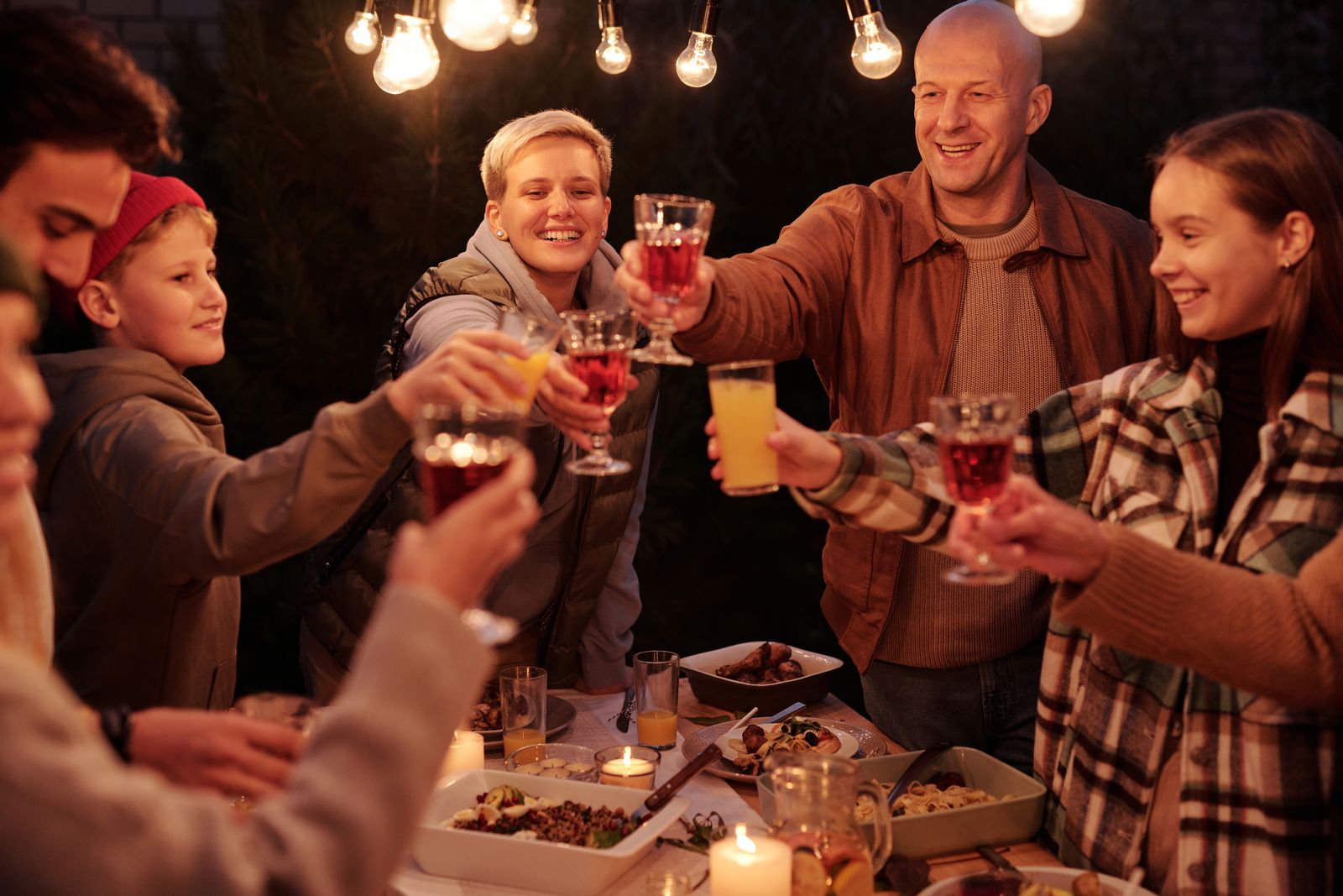 Friends toasting together at a backyard party beneath string lights