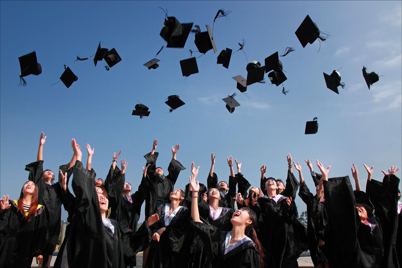 Graduates celebrating together and tossing their caps into the air